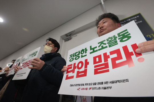 민주노총 건설노조원들이 14일 오전 서울 마포구 민주노총 건설노조 수도권북부지역본부에서 건설현장 불법행위 관련 압수수색 중인 경찰에 항의하는 팻말을 들고 구호를 외치고 있다. <연합뉴스>